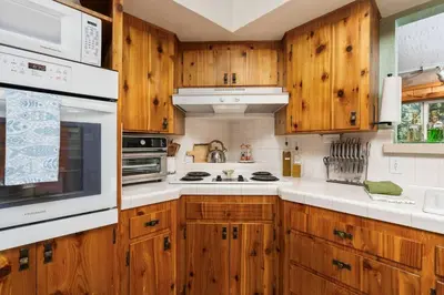 a kitchen with wooden cabinets and white appliances at Piece of Paradise Dream Deck AC in Shaver Lake