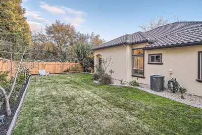 a backyard of a white house with a fence at Beautiful Granite Bay Home near Folsom Lake in Granite Bay