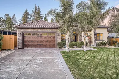 a house with a garage and a palm tree at Beautiful Granite Bay Home near Folsom Lake in Granite Bay