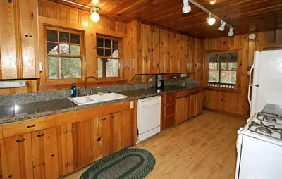 a kitchen with wooden cabinets and a white refrigerator at Spacious Riverfront Cabin Rental Perfect for Large Groups near Sonora, California in Strawberry