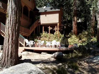 a cabin with chairs and tables in front of it at Spacious Riverfront Cabin Rental Perfect for Large Groups near Sonora, California in Strawberry