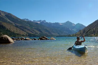 a man is in a kayak in the water at Rustic Trailer Rental on the Shores of Bridgeport Reservoir, California in Bridgeport