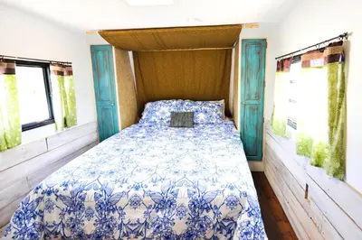 a blue and white bed in a room with windows at Rustic Trailer Rental on the Shores of Bridgeport Reservoir, California in Bridgeport