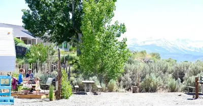 a group of people sitting on chairs under a tree at Rustic Trailer Rental on the Shores of Bridgeport Reservoir, California in Bridgeport