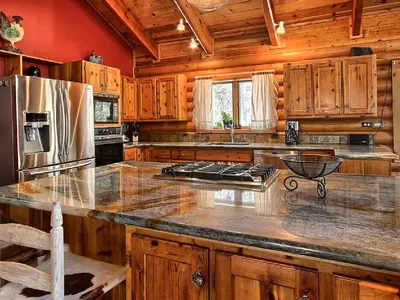 a kitchen with wooden cabinets and a granite counter top at Cozy Log Cabin near Yosemite National Park in California in Mariposa
