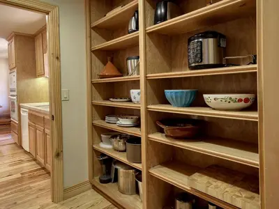a kitchen pantry with wooden shelves and bowls at Exceptionally Spacious Log Cabin for Groups in Mariposa, California in Mariposa