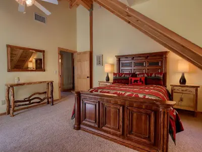 a bedroom with a large wooden bed and a staircase at Exceptionally Spacious Log Cabin for Groups in Mariposa, California in Mariposa