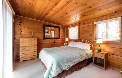 a bedroom with a bed in a wooden room at Cozy Riverside Cabin Rental with Easy Access to Chilnualna Falls in California in Wawona