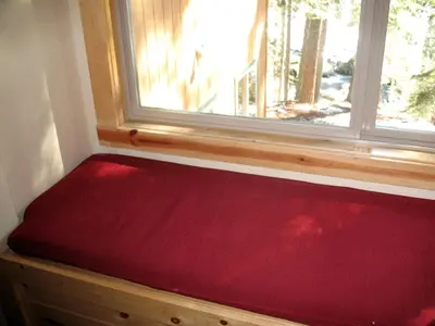 a red mattress sitting under a window in a room at Exceptional Riverside Cabin Rental in the Trees near Pinecrest Lake, California in Strawberry