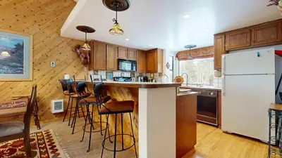 a kitchen with a white refrigerator and a bar with stools at Serene Sierra Sanctuary Experience Mammoth Magic in Mammoth Lakes