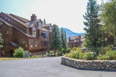 a large house with a stone wall in front of a street at Aspen Creek #119 Shared Pool Hot Tub & BBQ in Mammoth Lakes