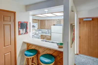 a kitchen with a counter with two blue stools at Aspen Creek #119 Shared Pool Hot Tub & BBQ in Mammoth Lakes