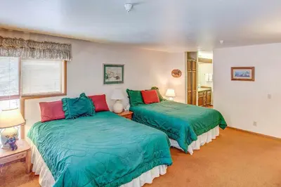 a bedroom with two beds with green comforters at Aspen Creek #119 Shared Pool Hot Tub & BBQ in Mammoth Lakes