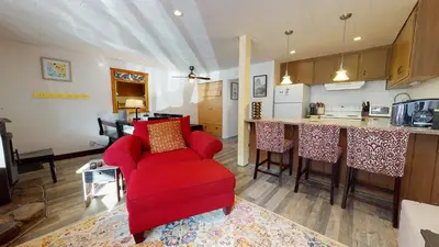 a living room with a red chair and a kitchen at Sierra Manors In the Heart of Mammoth in Mammoth Lakes
