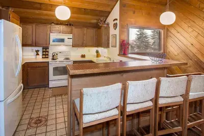 a kitchen with a counter with chairs and a refrigerator at Snowcreek #059 Near Shuttle & Activities in Mammoth Lakes