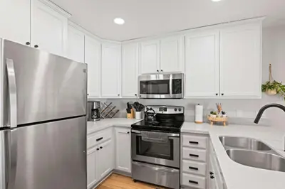 a kitchen with white cabinets and a stainless steel refrigerator at St Anton Getaway Shared BBQ Pool & Hot Tub in Mammoth Lakes