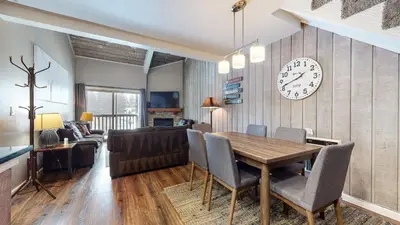 a dining room and living room with a table and a clock at Chamonix #70 Near Yearly Outdoor Activities in Mammoth Lakes