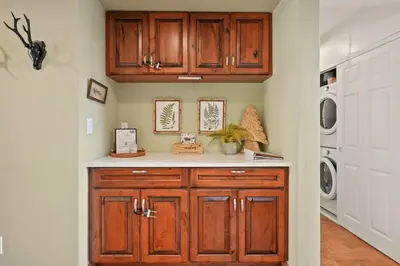 a kitchen with wooden cabinets and a washer and dryer at Bearfoot Cabin 15 Min to Yosemite Gate! in Oakhurst