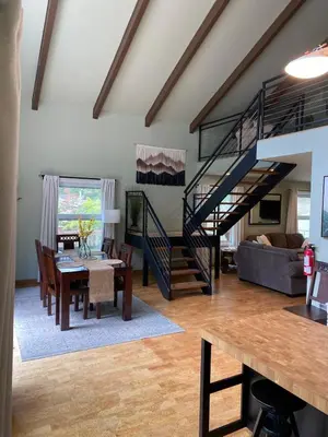 a living room with a staircase and a dining room at Bearfoot Cabin 15 Min to Yosemite Gate! in Oakhurst