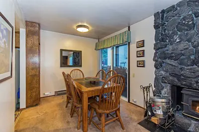 a dining room with a table and chairs and a stone fireplace at Horizons Year-Round Fun with Rec Room in Mammoth Lakes