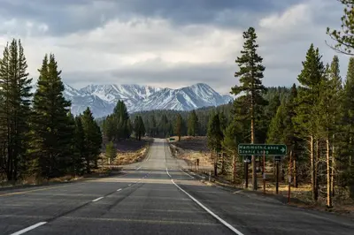 an empty road with snow capped mountains in the distance at Horizons Communal Sauna & Hot Tub in Mammoth Lakes