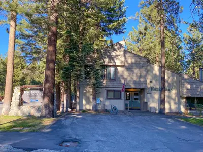 a white house with trees in front of a driveway at Horizons Condo with Communal Clubhouse in Mammoth Lakes