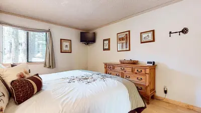 a bedroom with a bed and a dresser and a television at Summit Cozy Condo Getaway in Mammoth Lakes