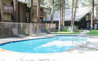 a swimming pool with two chairs and a building at Sunshine Village #142 Close to Shops & Eats in Mammoth Lakes
