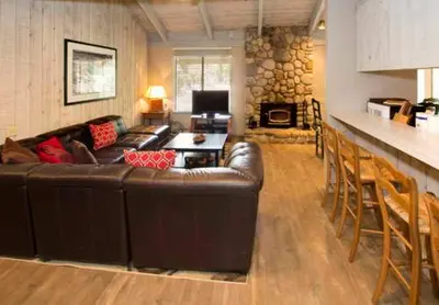 a living room with a brown leather couch and a fireplace at Sunshine Village #142 Close to Shops & Eats in Mammoth Lakes