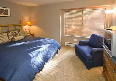 a bedroom with a bed and a chair and a television at Sunshine Village #142 Close to Shops & Eats in Mammoth Lakes