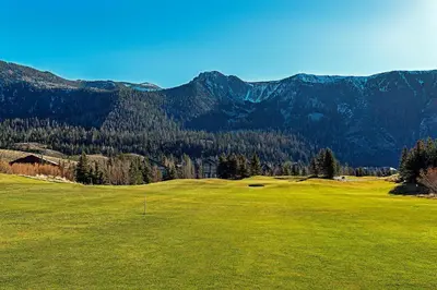 a green golf course with mountains in the background at An Adventure of a Lifetime 3 BDR 5 Min to Skiing in Mammoth Lakes