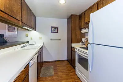 a kitchen with a white refrigerator and wooden cabinets at Viewpoint #131 Walk to Eats & Entertainment in Mammoth Lakes