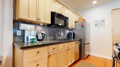 a kitchen with wooden cabinets and a stainless steel refrigerator at Villa De Los Pinos Year-Round Activities Nearby Shopping & Restaurants in Mammoth Lakes