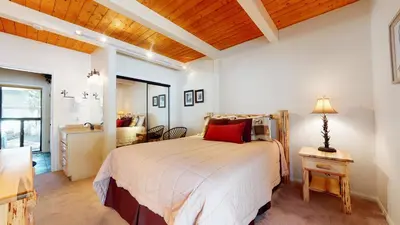 a bedroom with a bed and a table with a lamp at Villa De Los Pinos Year-Round Activities Nearby Shopping & Restaurants in Mammoth Lakes
