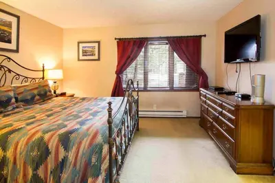 a bedroom with a bed and a dresser and a television at Winterset #28 Shared Hot Tub & Sauna in Mammoth Lakes