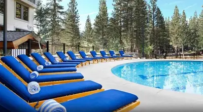 a row of blue lounge chairs next to a swimming pool at 2 BDR Family Resort Condo with Pool Lounge & Mountain Views in Mammoth Lakes