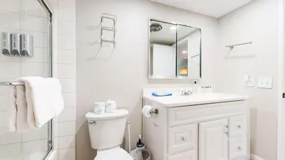 a white bathroom with a toilet and a sink at Mammoth Getaway - Chic Condo in Mammoth Lakes