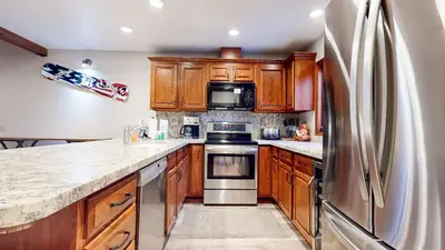 a kitchen with wooden cabinets and a stainless steel refrigerator at Mammoth Pines #02 - Year-Round Activities in Mammoth Lakes