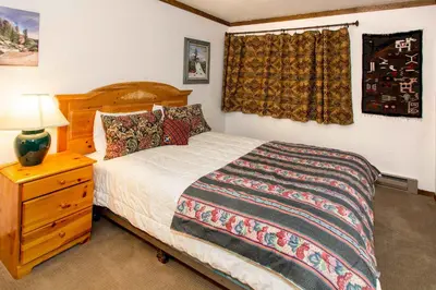 a bedroom with a bed and a dresser with a lamp at Mammoth Point #129 - Balcony with Mountain Views in Mammoth Lakes