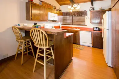 a kitchen with a counter and two chairs at a bar at Mammoth Point #129 - Balcony with Mountain Views in Mammoth Lakes