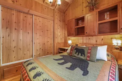 a bedroom with a bed with wooden walls and cabinets at The Cozy Cub Cabin 7 Min to Lake in South Lake Tahoe