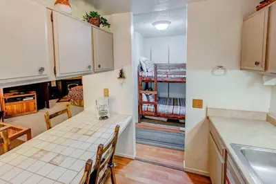 a kitchen with a table and a room with a bunk bed at Mountain Shadows #F02 - Near Shuttle & Shopping in Mammoth Lakes