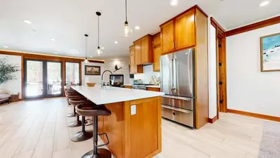 a kitchen with wooden cabinets and a stainless steel refrigerator at Obsidian Dreaming - On the Sierra Star Golf Course in Mammoth Lakes