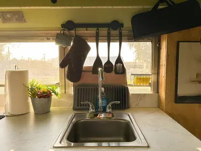 a kitchen sink with utensils hanging from a wall at The Magic Skoolie in Visalia