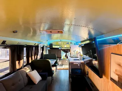 a living room with a couch and chairs in an rv at The Magic Skoolie in Visalia