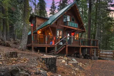 a log cabin in the woods with lights on at Tahoe Pines Cabin in Homewood