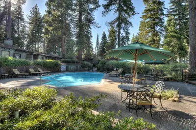 a pool with a table and an umbrella at Waters Edge Oasis - Shared Pool & Pier Access in Tahoma