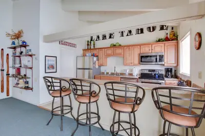 a kitchen with wooden cabinets and four bar stools at Waters Edge Vista - HOA Pool & Pier Access in Tahoma