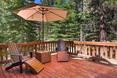 a patio with two chairs and an umbrella on a deck at Alpine Gem Near Homewood Mountain in Tahoma