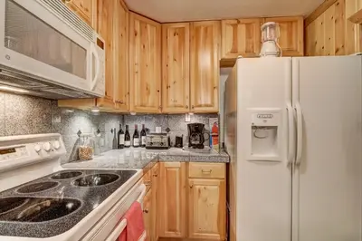 a kitchen with wooden cabinets and a white refrigerator at Alpine Meadows Peak 15 Min to Commons Beach in Alpine Meadows